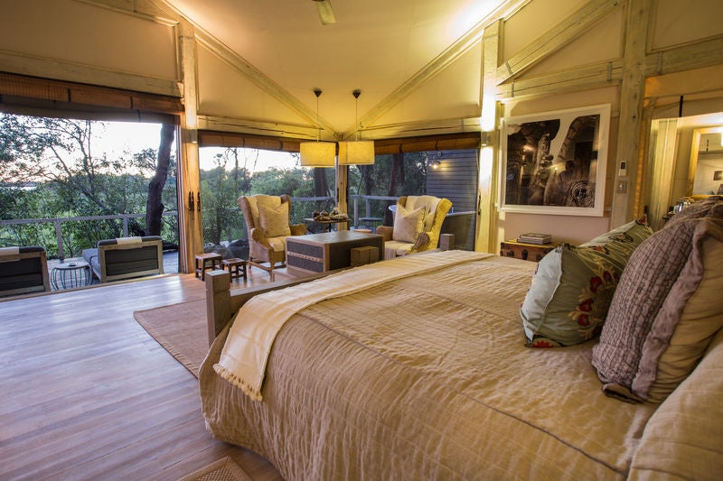 Elevated luxury safari lodge with tented suites overlooking vast Okavango wetlands, featuring private plunge pools and modern décor