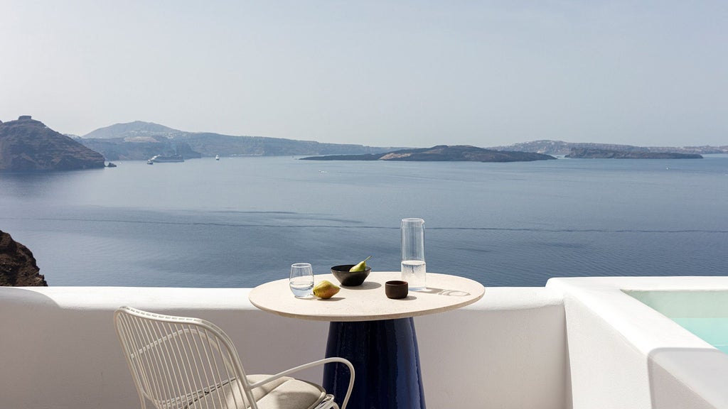 Luxurious white-washed Cycladic suite with private plunge pool, panoramic Aegean Sea view, minimalist design, and elegant contemporary furnishings in Oia, Santorini.