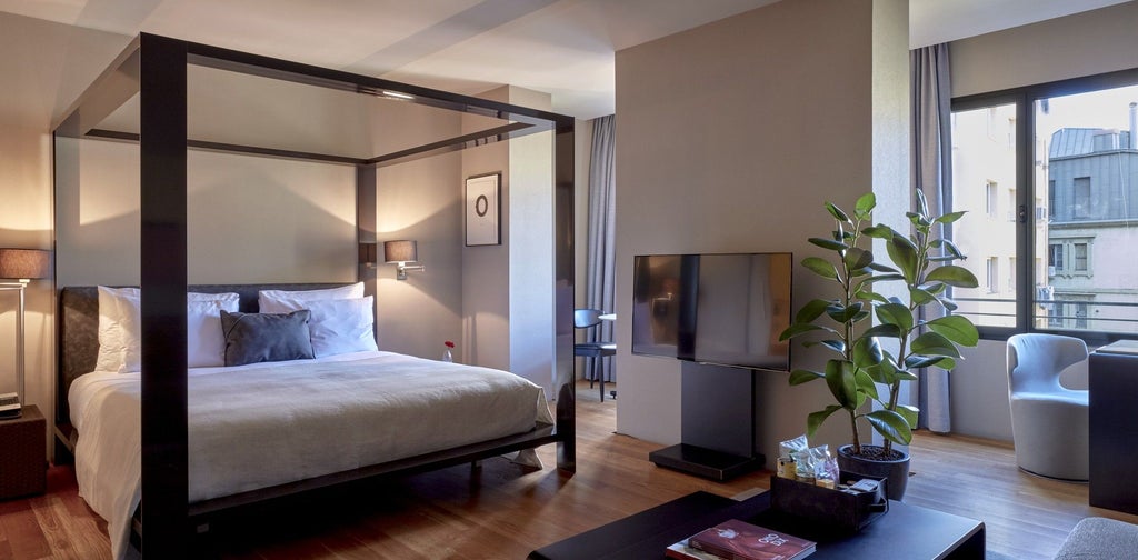 Modern, spacious hotel room with sleek minimalist design, panoramic city views, natural light, elegant wood tones, and contemporary furnishings in Sir Victor boutique hotel, Barcelona