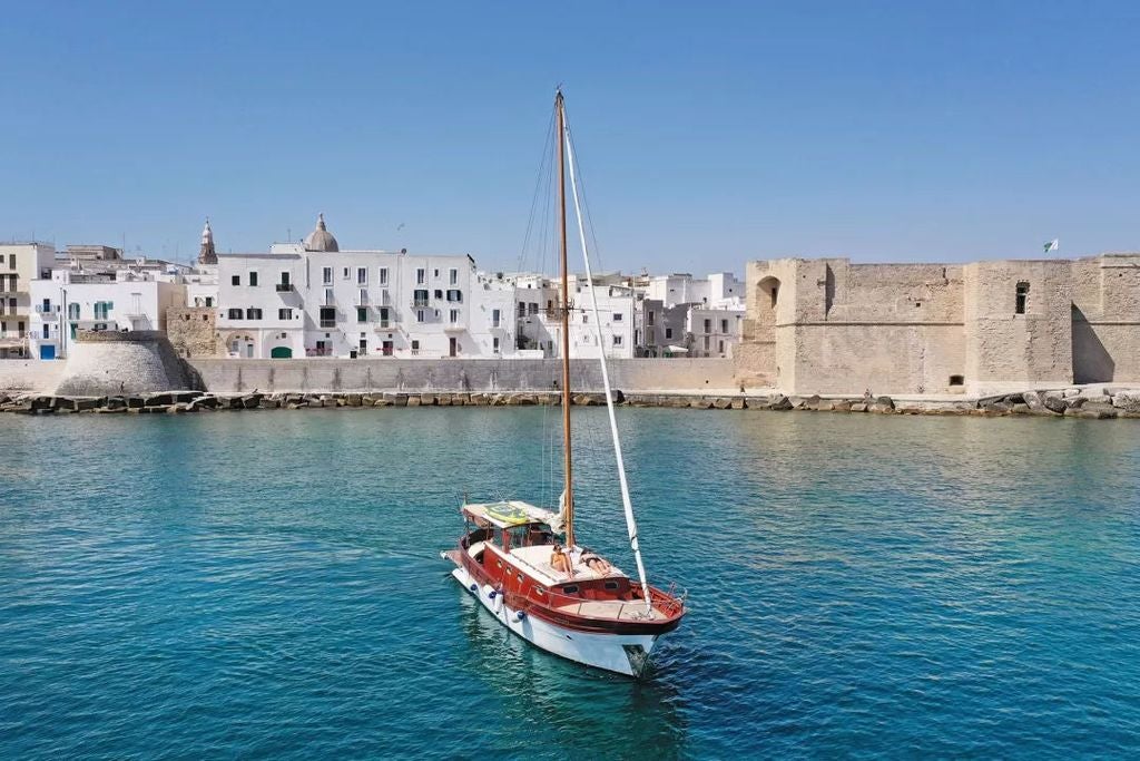 Upscale Italian farmhouse hotel with whitewashed stone walls, traditional architecture, and meticulously landscaped Mediterranean gardens