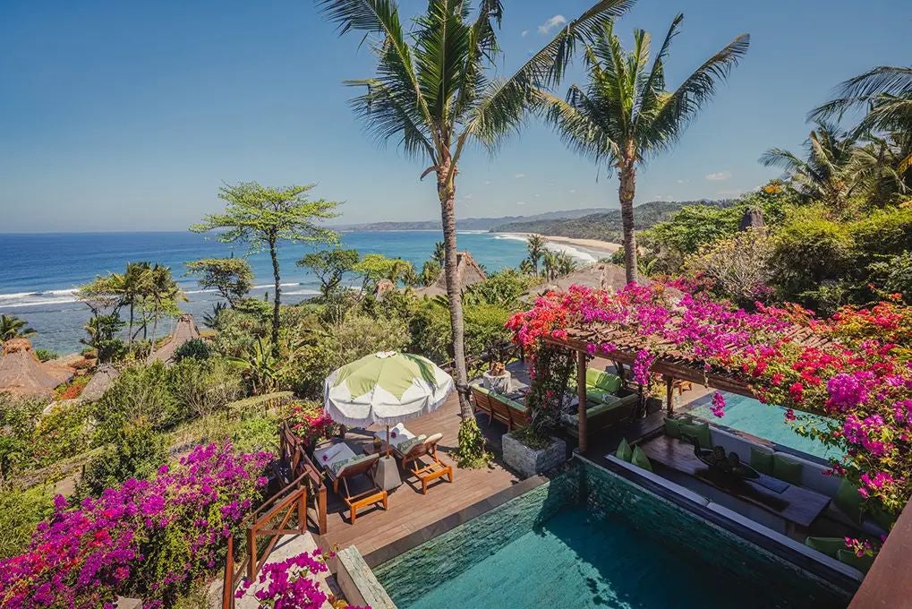 Luxurious Puncak Estate villa overlooking lush tropical landscape, featuring elegant wooden interiors, expansive windows, and private infinity pool at NIHI Sumba resort