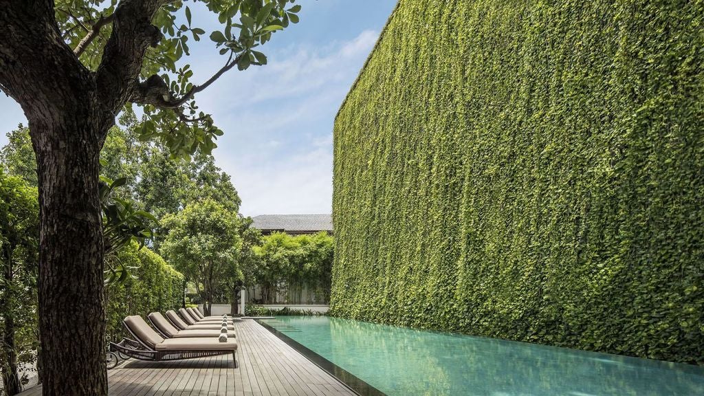 Colonial-style luxury resort in Chiang Mai with ornate white pillars, wraparound veranda, and lush tropical gardens under blue skies