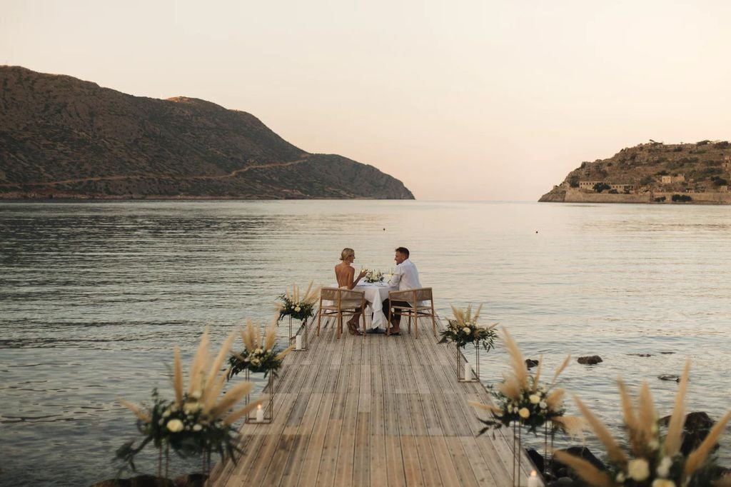 Luxury infinity pool overlooking Aegean Sea at Blue Palace resort, with white loungers and traditional Greek architecture at sunset