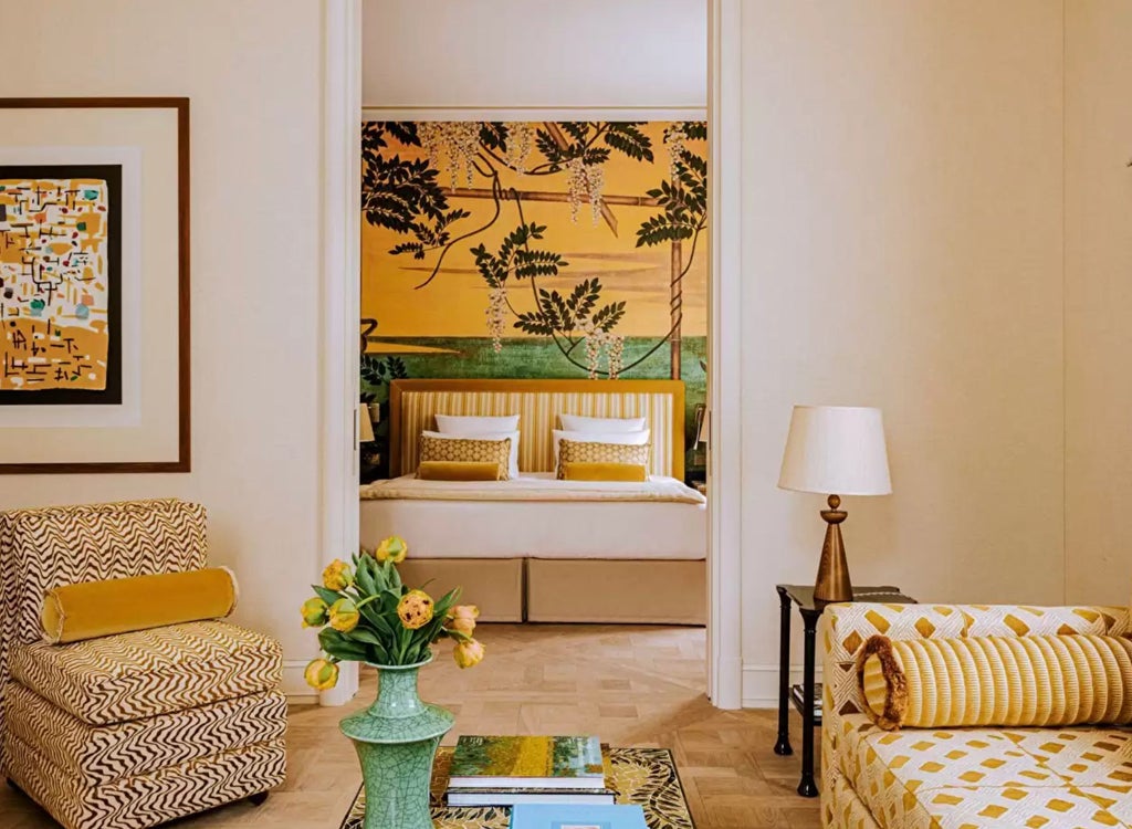 Opulent Junior Suite with draped canopy bed, gold accents, period furniture, and large windows overlooking Parisian gardens