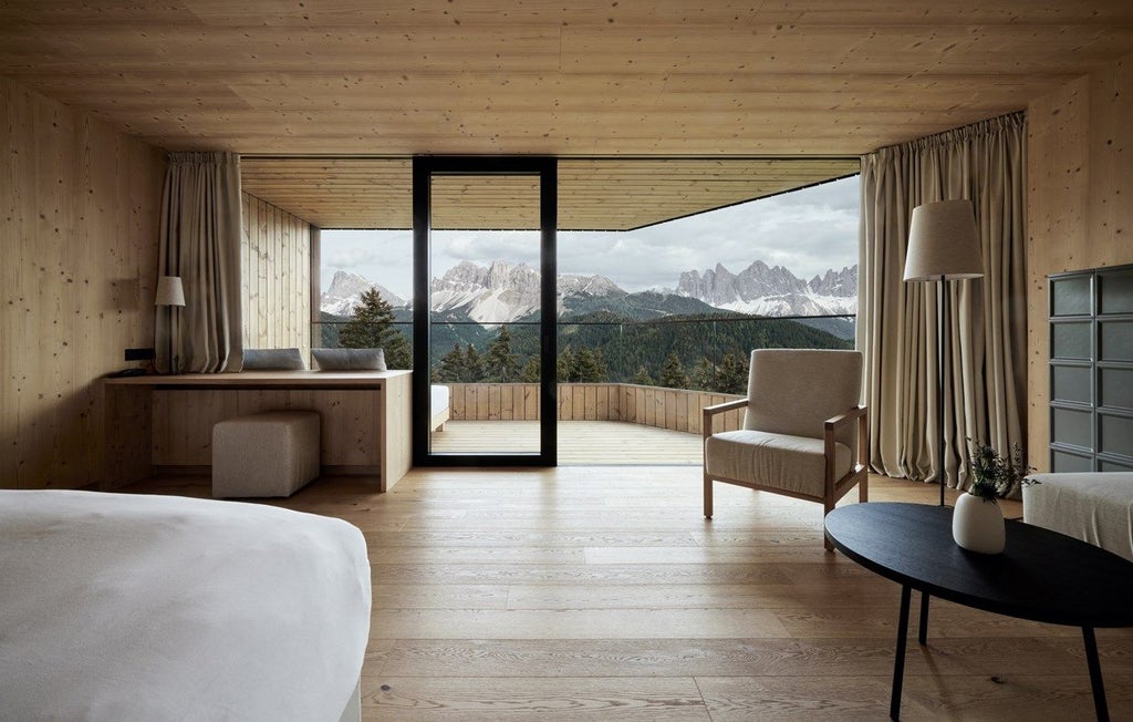 Modern luxurious suite with panoramic mountain views, king bed with white linens, freestanding bathtub, and minimalist wooden decor