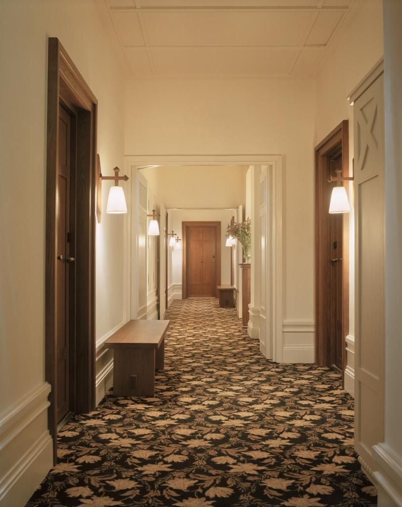 Elegant Parisian hotel suite with plush cream upholstered armchair, ornate gold-framed mirror, and soft neutral color palette highlighting refined French design