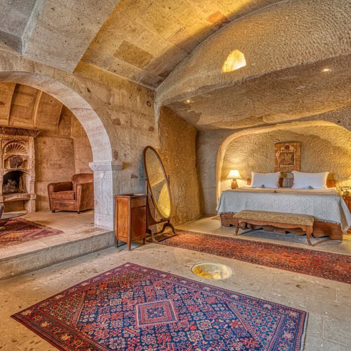 Elegant superior suite at Museum Hotel with ornate Turkish decor, stone walls, luxurious bed, and panoramic landscape view through arched window