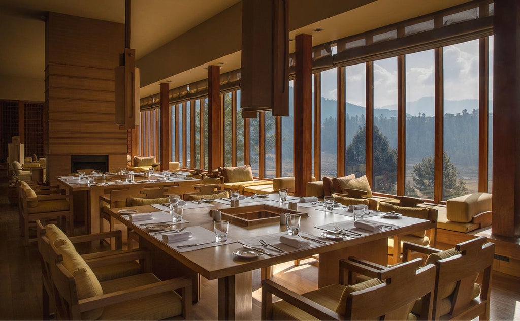 Luxurious mountain lodge with floor-to-ceiling windows overlooking misty Gangtey Valley, featuring modern wood and stone architecture