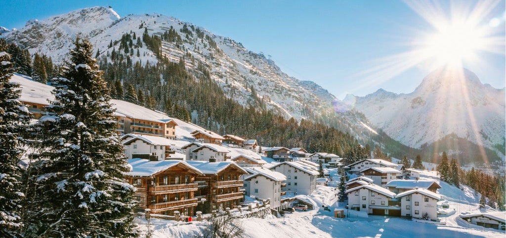 Luxurious alpine chalet at scenset with snow-capped mountain peaks, elegant wooden balconies, and warm, inviting winter landscape in Austria.