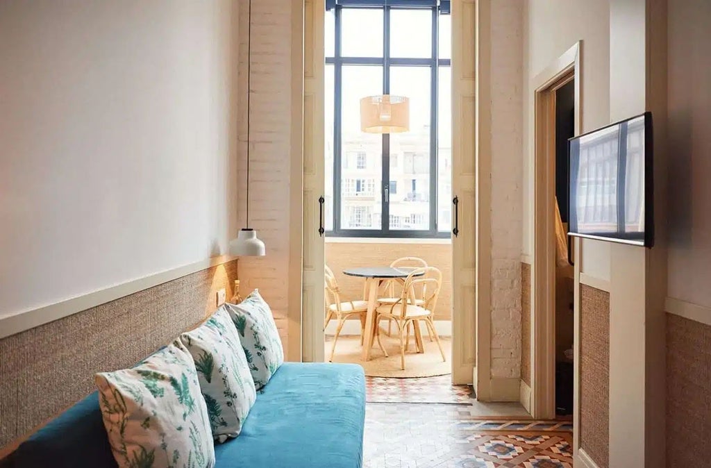 Elegant Barcelona hotel courtyard at Casa Bonay, featuring lush greenery, vintage tiles, and sunlight casting warm shadows on historic architecture