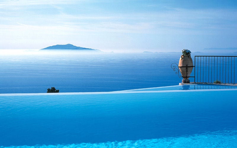 Elegant cliffside hotel Caesar Augustus in Capri with infinity pool overlooking Bay of Naples and Mount Vesuvius at sunset