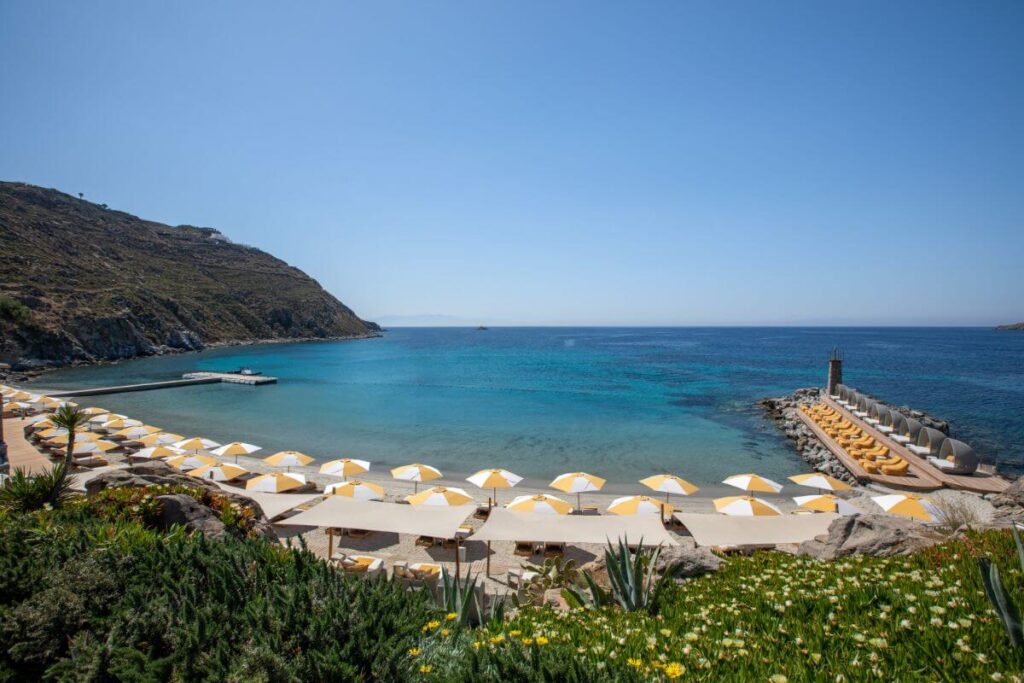 Elegant oceanfront resort in Mykonos with infinity pools cascading toward Aegean Sea, white cycladic architecture and private cabanas