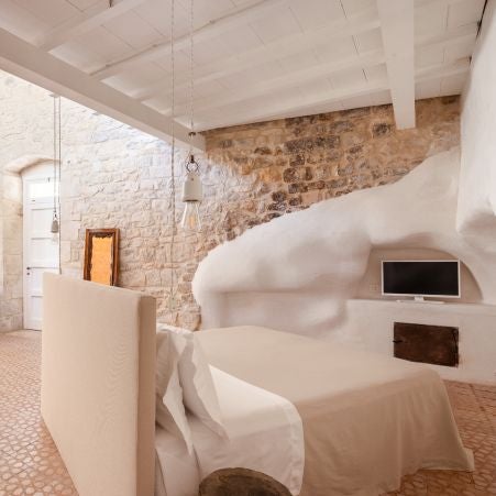 Elegant Italian boutique hotel room with minimalist design, warm wooden floors, and soft natural light illuminating rustic architectural details in Sicilian style