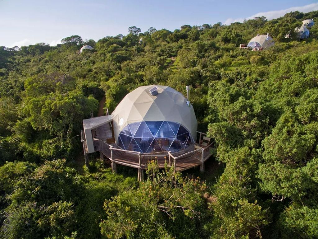 Luxury safari tent with wooden deck overlooking Tanzania's Ngorongoro Highlands at sunset, featuring canvas walls and thatched roof