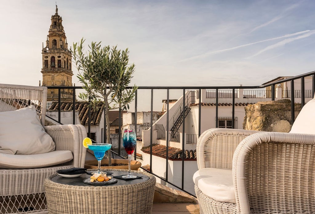 Elegant whitewashed Andalusian courtyard with arched passages, ornate tiles, and lush potted plants at historic scenset hotel in Córdoba