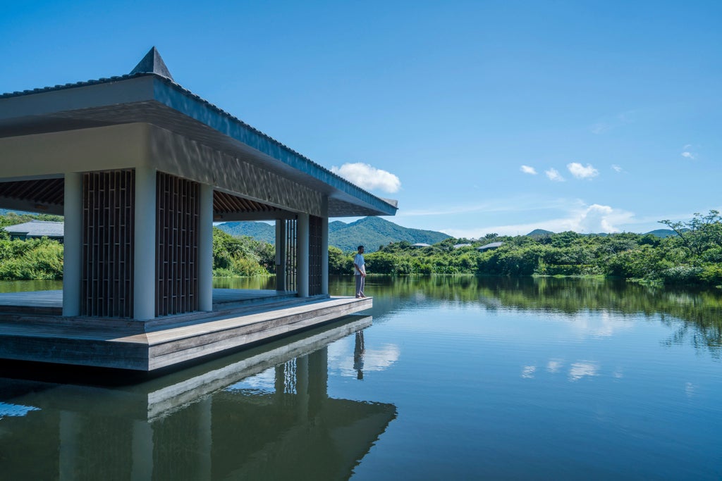 Luxury cliffside villa with infinity pool overlooking pristine turquoise bay and forested mountains along Vietnam's dramatic coastline