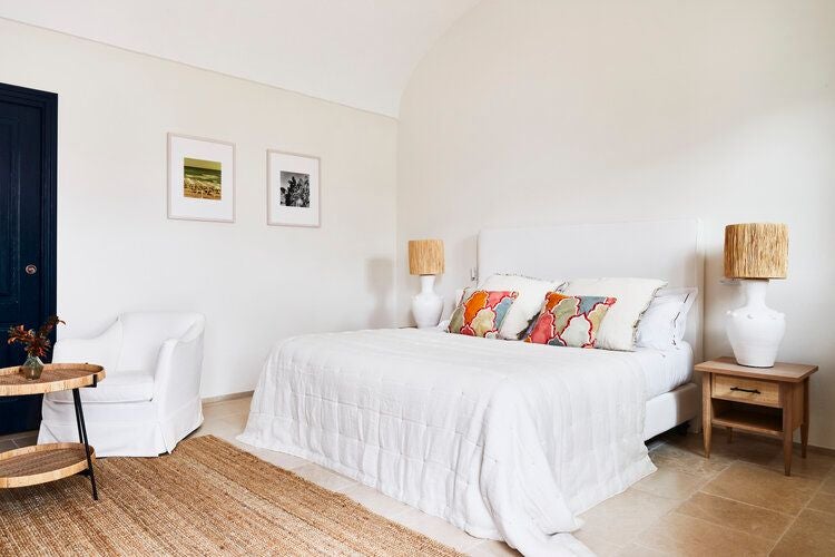 Rustic stone courtyard with elegant white-washed walls, traditional Italian architecture, soft sunlight, and intimate seating in a luxurious Puglia masseria