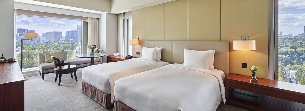 Luxurious hotel room with modern Japanese design, floor-to-ceiling windows overlooking Wadakura Fountain Park, elegantly furnished twin/king bed, and private balcony.