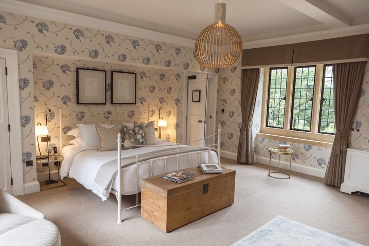 Elegant chestnut-toned bedroom at Foxhill Manor, featuring plush bedding, ornate wooden furniture, and soft ambient lighting in a luxurious UK country estate setting.