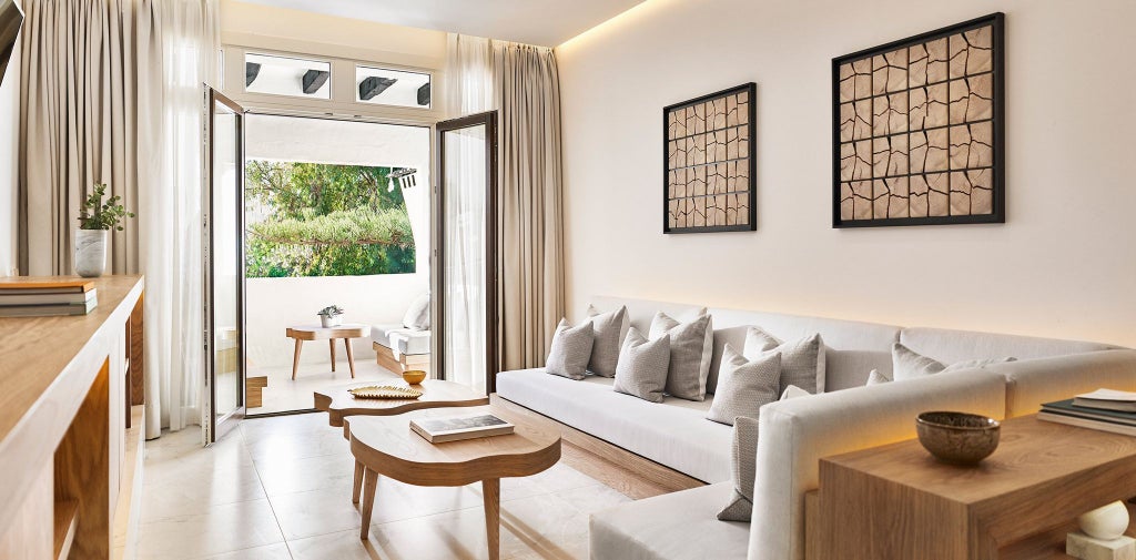 Luxurious junior suite at Nobu Hotel Marbella, featuring modern minimalist design with white bedding, sleek furniture, and panoramic coastal view