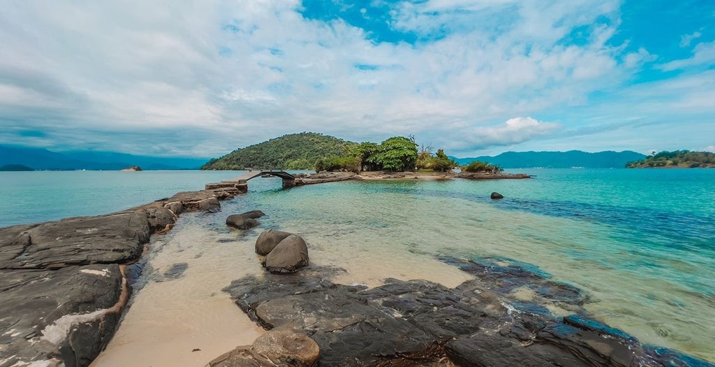 Luxurious beachfront resort with modern white buildings nestled between lush mountains and a private marina on Brazil's emerald coast