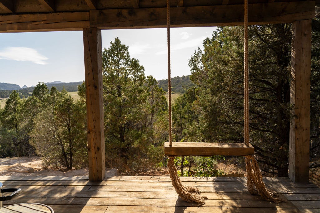 Rustic wooden lodge interior with panoramic mountain views, plush king bed, warm earth tones, and elegant western-inspired decor in scenset mountain retreat