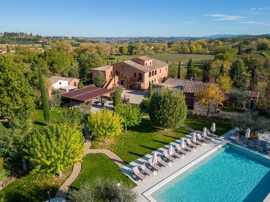 Elegant Italian villa hotel with stone facade, arched windows, terracotta roof, and manicured garden set against rolling Tuscan hills