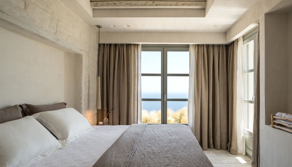 Minimalist white and blue hotel room with Aegean Sea view, sleek design, private balcony, and elegant Cycladic architectural elements at Verina Astra resort in Sifnos, Greece.