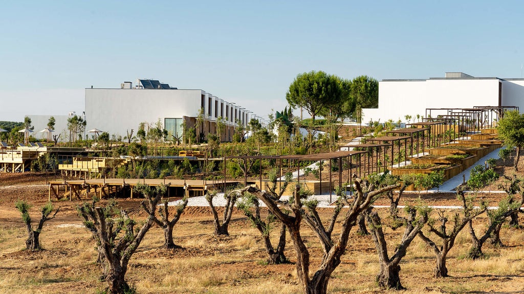 Modern luxury hotel exterior featuring sleek white architecture, infinity pool overlooking Alentejo countryside at sunset in Portugal