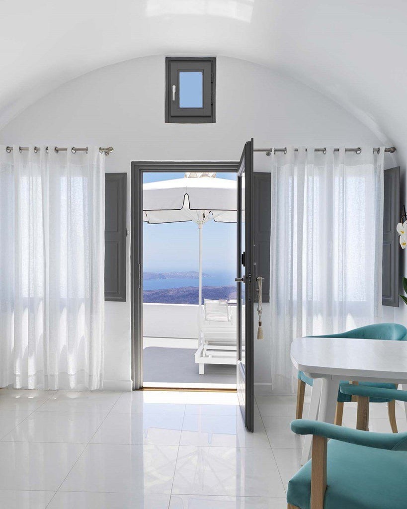 Luxurious white-walled Junior Suite with panoramic Aegean Sea view, minimalist design, private balcony, and elegant Santorini architectural style