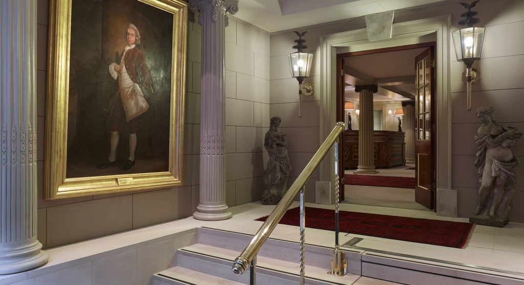 Luxurious boutique hotel room with ornate Georgian-style decor, rich velvet furnishings, and intricate period details showcasing elegant British hospitality