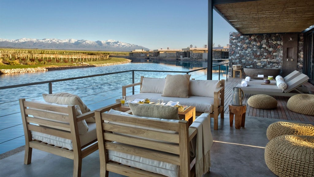 Luxurious mountain resort spa with modern stone architecture nestled in Argentinian vineyard valley under blue autumn skies