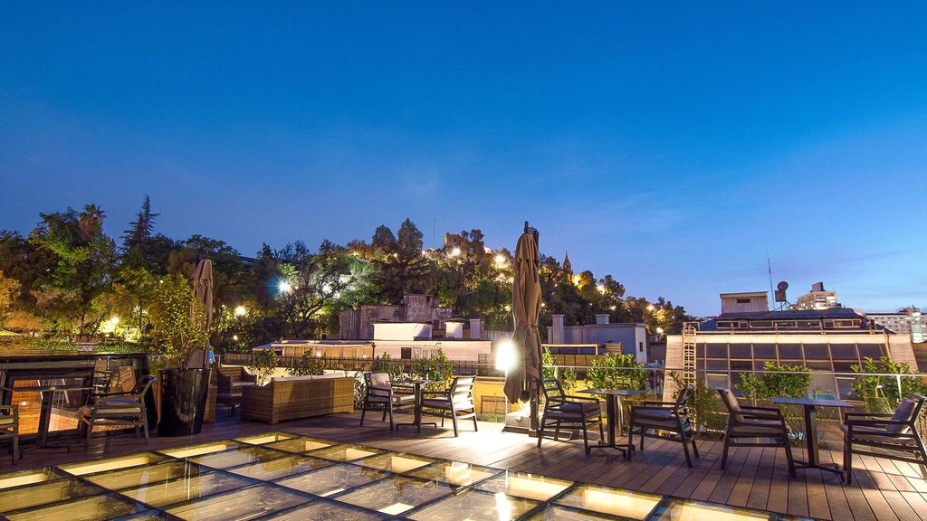 Elegant historic mansion turned boutique hotel with white facade, arched windows, and ornate columns, surrounded by palm trees in Santiago