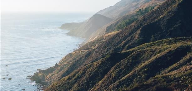 Luxurious Pacific House Suite with panoramic ocean views, elegant wood furnishings, and floor-to-ceiling windows overlooking scenic Big Sur coastline