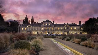 Elegant 18th-century manor hotel nestled in lush Yorkshire countryside, featuring grand stone facade, manicured gardens, and pristine landscaping.