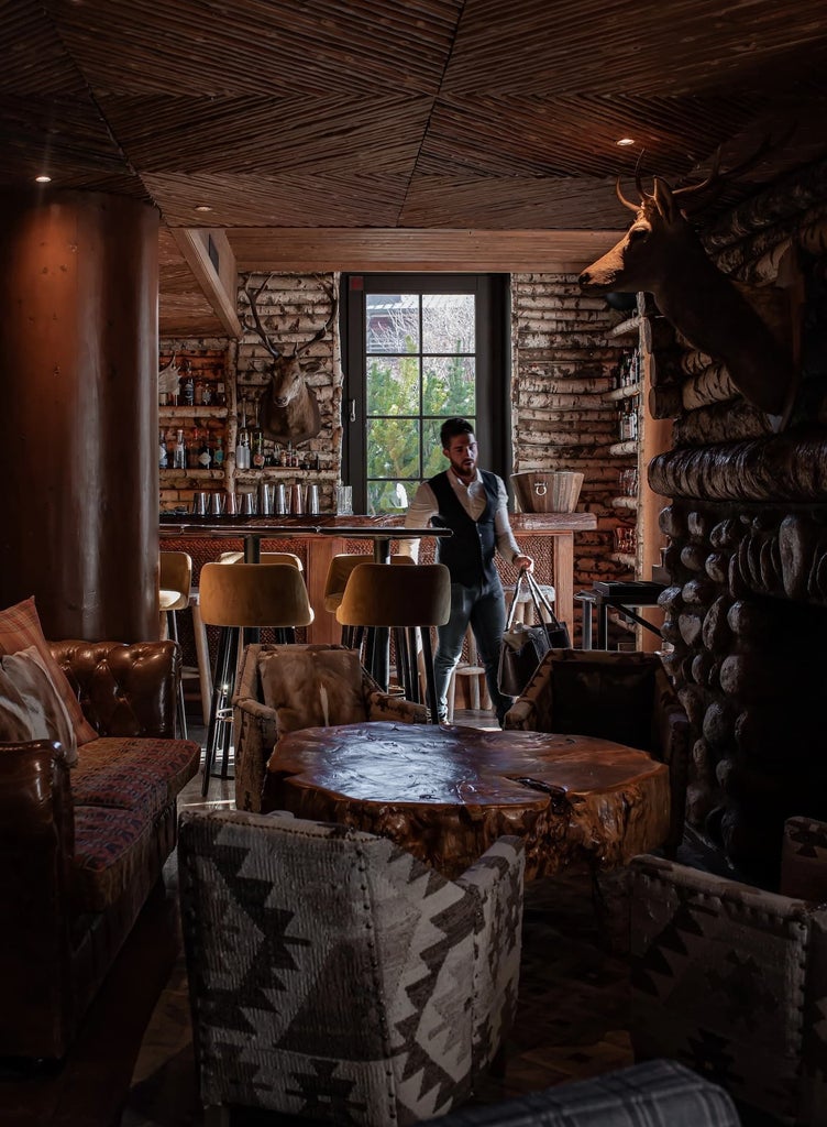 Elegant wooden chalet-style lodge nestled in snow-covered alpine landscape, luxurious French mountain hotel with warm lighting and majestic pine forest backdrop