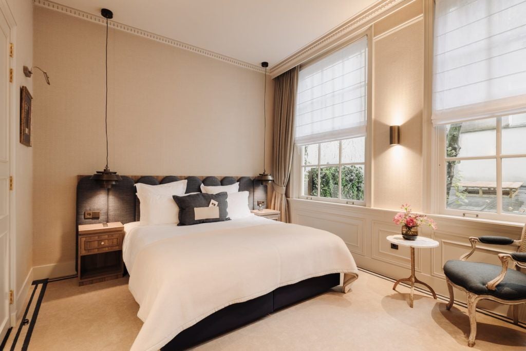 Elegant hotel room with modern minimalist design, soft blue walls, plush white bedding, and artistic Little Prince-themed decor in a Netherlands boutique hotel