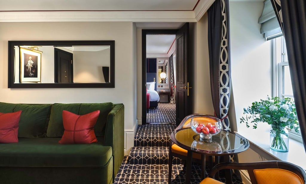 Elegant green-toned luxury suite with plush emerald velvet armchair, sophisticated artwork, and refined contemporary British design in scenset hotel