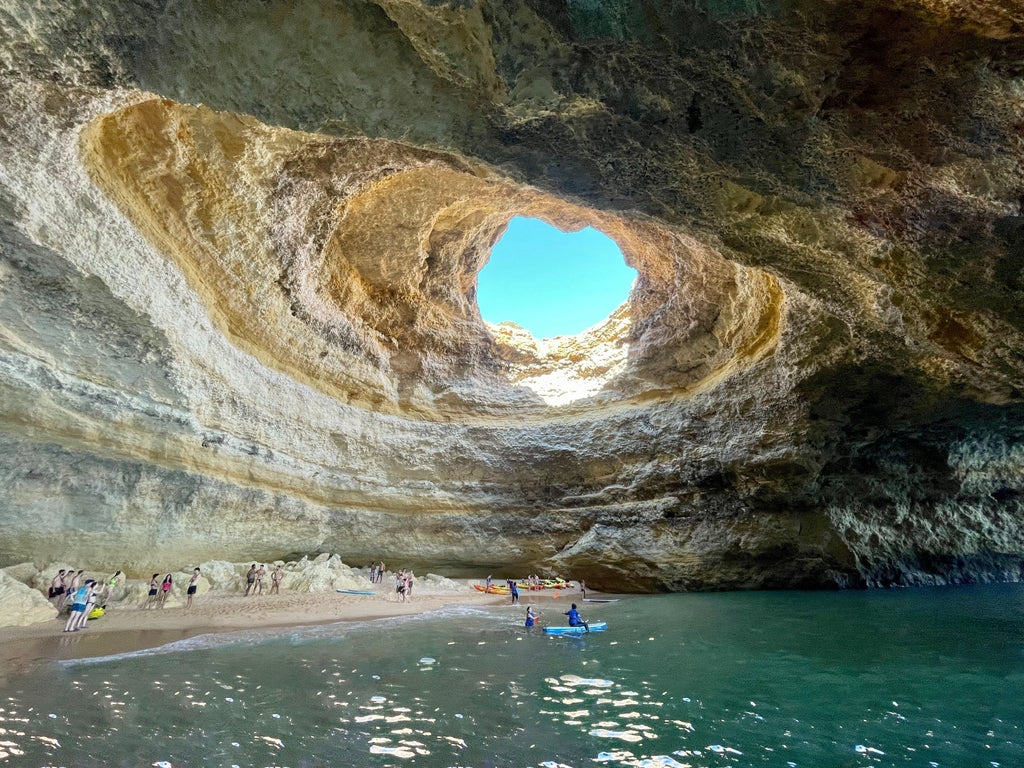 Pristine turquoise waters of the Algarve coastline, luxurious kayak gliding through Benagil Cave's dramatic rock formations and sunlight-pierced azure waters