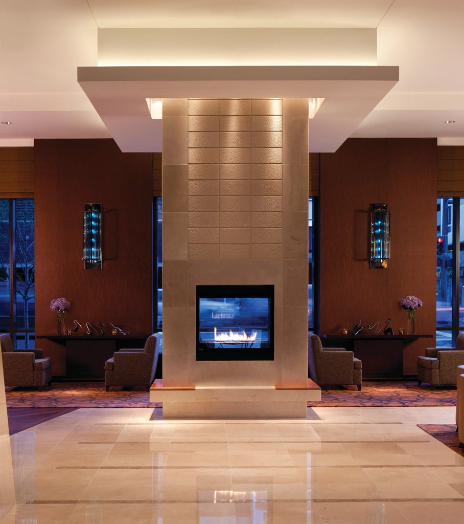 Luxurious Four Seasons Denver hotel features a modern glass and stone facade, with mountain views and elegant entrance under a curved awning