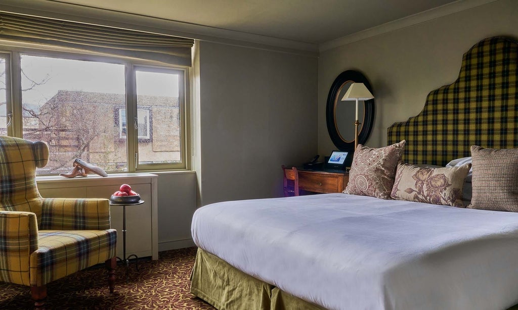 Elegant cozy double room with warm wood furnishings, plush bedding, and classic British countryside charm at historic Lygon Arms hotel