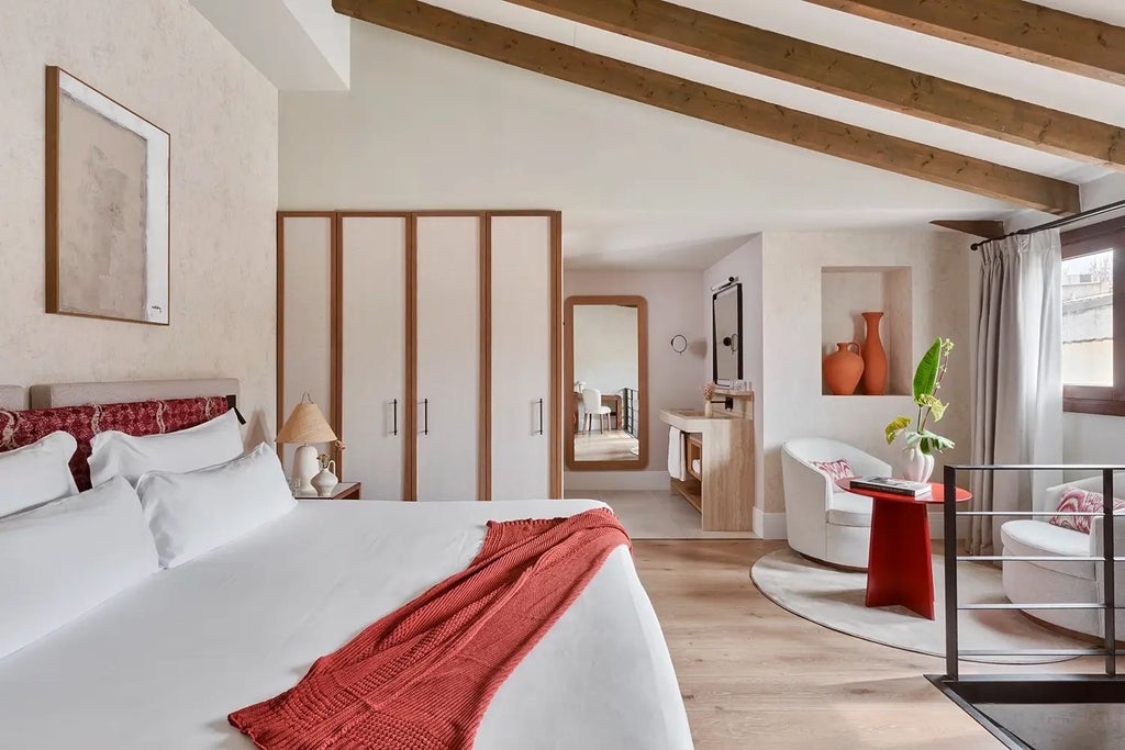 Elegant duplex hotel room at Scenset Terra Santa with rustic stone walls, wooden beams, plush white bedding, and warm Mediterranean design aesthetic