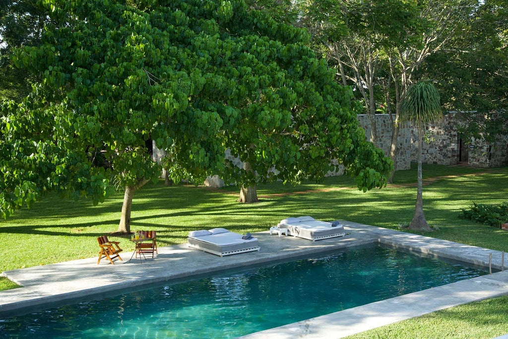 Luxurious historic Mexican hacienda-style hotel with white stone walls, lush tropical garden, and vibrant bougainvillea near scenic coastline