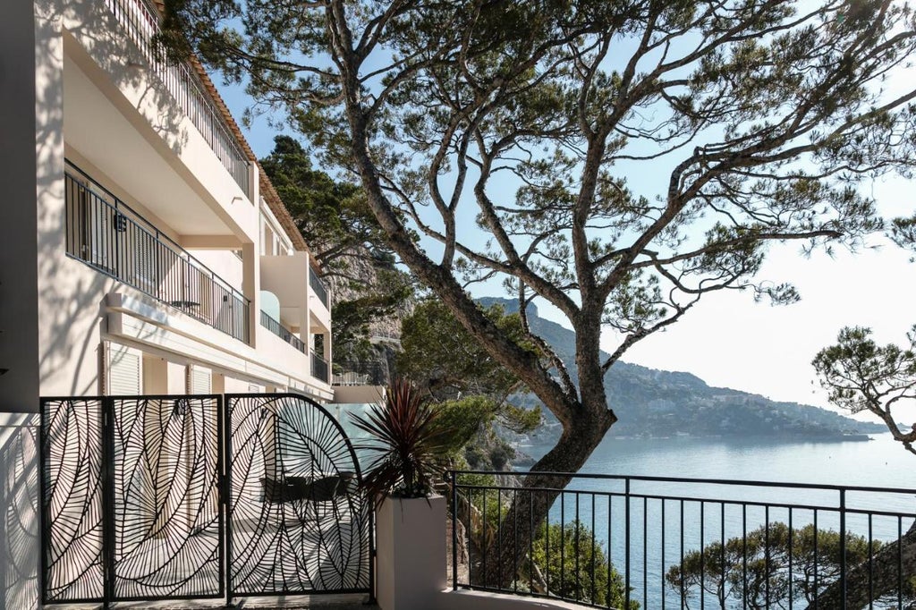 Luxury seaside hotel on French Riviera with white Mediterranean-style architecture perched on cliffside peninsula overlooking azure waters