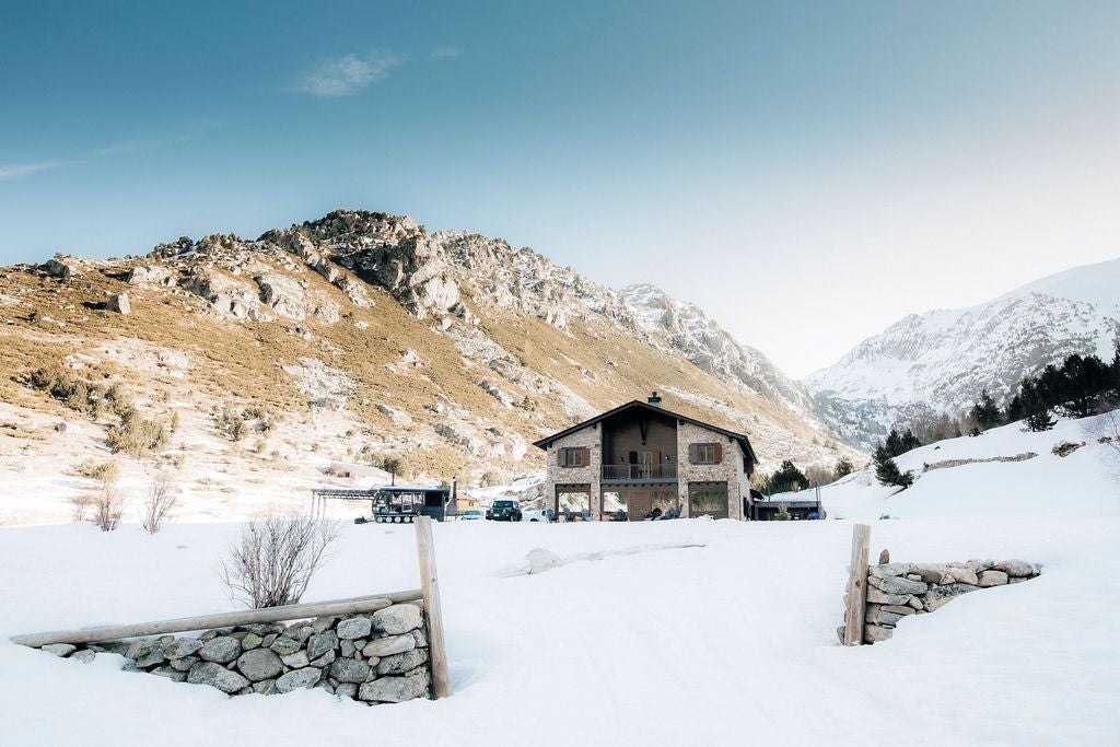 Luxurious mountain lodge nestled in Andorran peaks, showcasing rustic stone exterior, wooden balconies, and panoramic alpine landscape at golden hour.