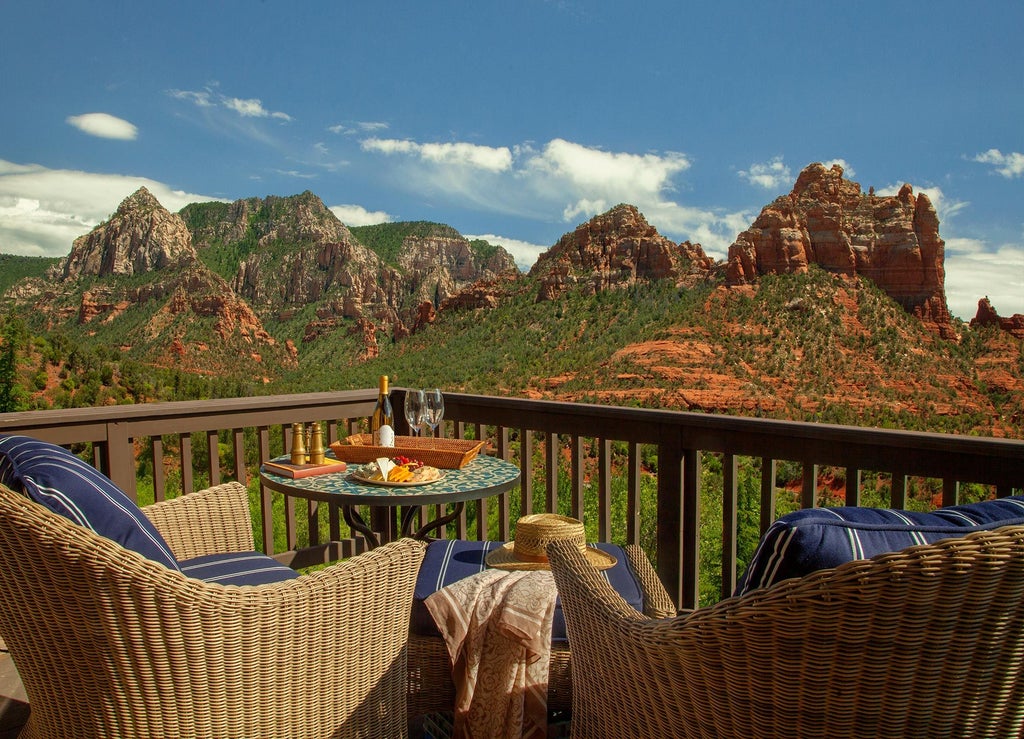 Luxurious mountainside resort with stone facade, private balconies and outdoor terrace nestled against red rock cliffs at sunset