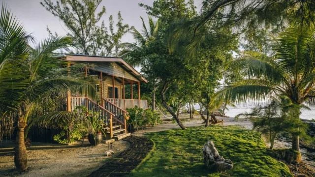 Luxurious Argentine hotel room with coral-toned decor, elegant wooden furniture, plush bedding, and soft ambient lighting in a tropical-inspired setting