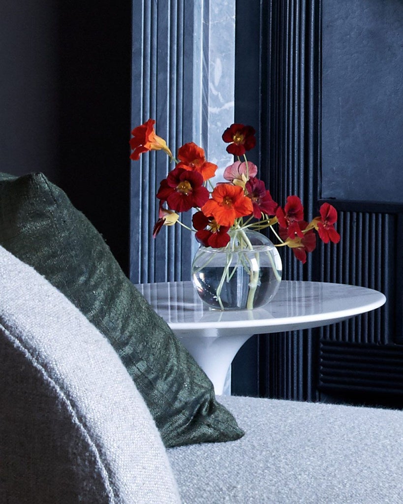 Elegant coppice room at Heckfield Place, featuring soft neutral tones, vintage furnishings, natural light, and views of lush countryside through large windows.