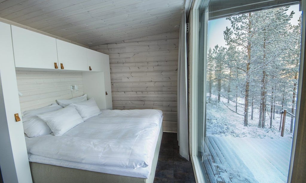 Modern Nordic glass cabin with panoramic windows overlooking snowy forest, featuring minimalist design and warm interior lighting at dusk in Finnish Lapland