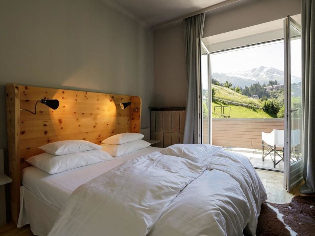 Elegant alpine hotel exterior with modern glass balconies, wooden facade and mountain backdrop in snowy Bad Gastein, Austria